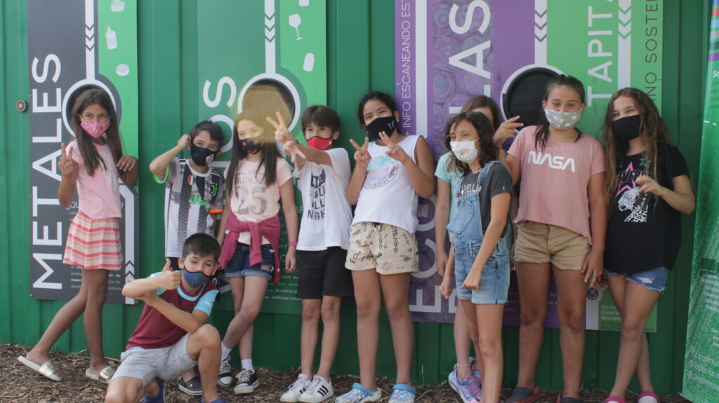 Grupo de niños y niñas frente a un punto de acopio de reciclables