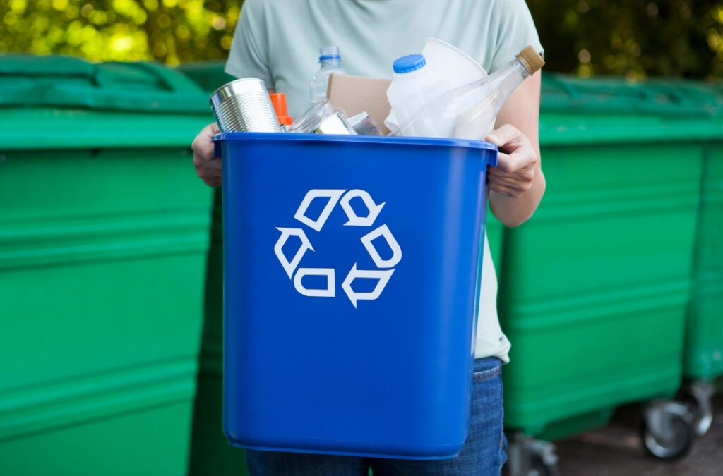 Foto de una persona sosteniendo un tacho con reciclables.